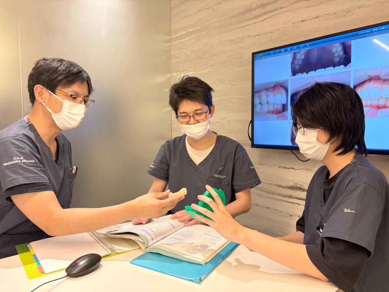 歯科医師が資料と模型を使って若手スタッフに説明する様子